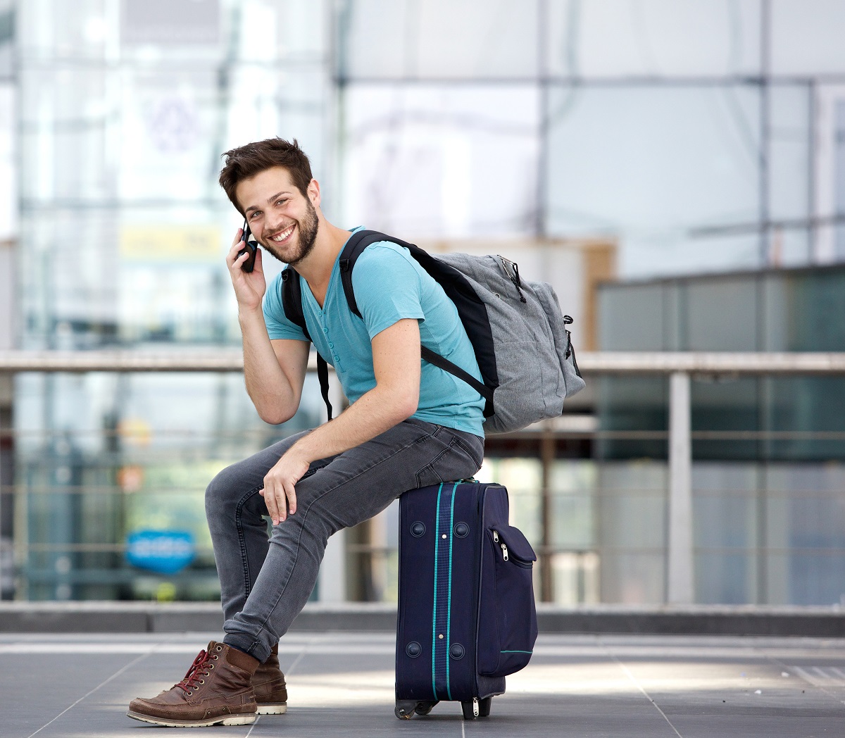 Young man sitting on his suitcase in the airport