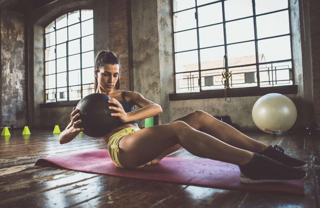 Woman exercising on a mat using a medicine ball.