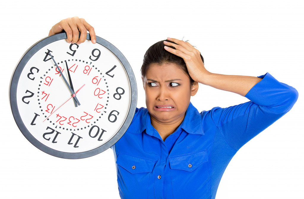 woman holding a clock very stressed by lack of time