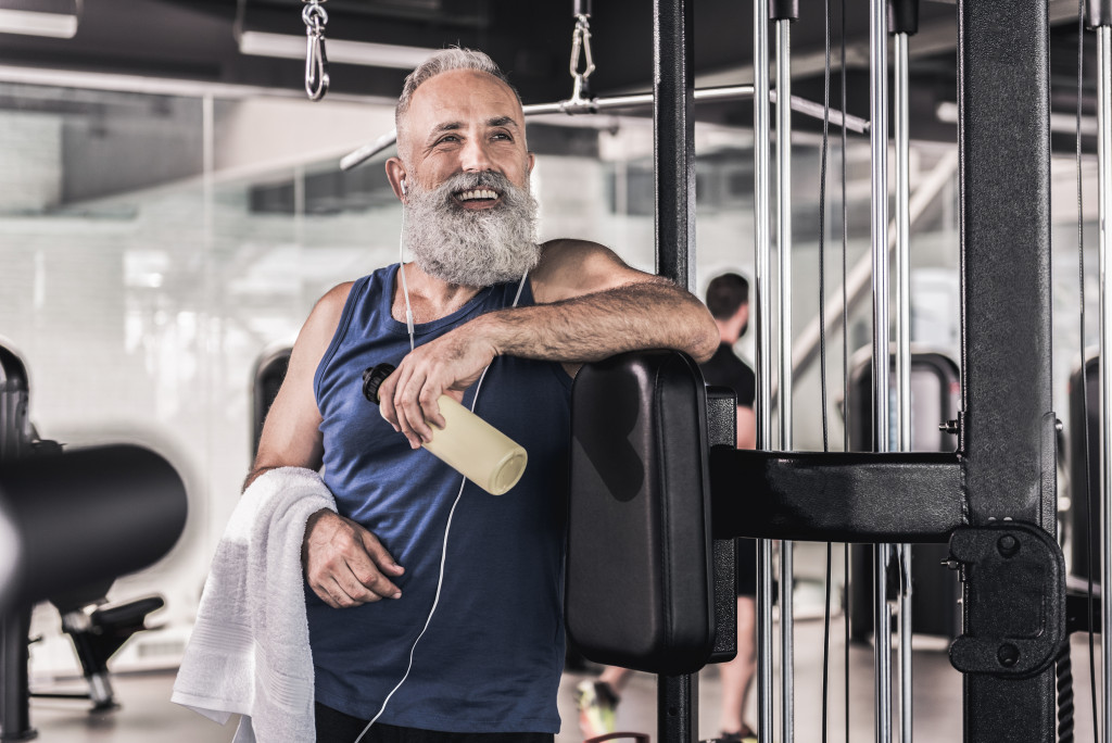 elderly man smiling while resting in proper gear at the gym