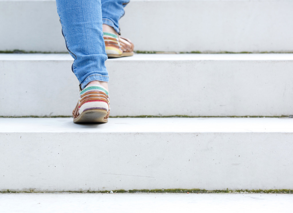 A person wearing jeans and sneakers walking up stairs