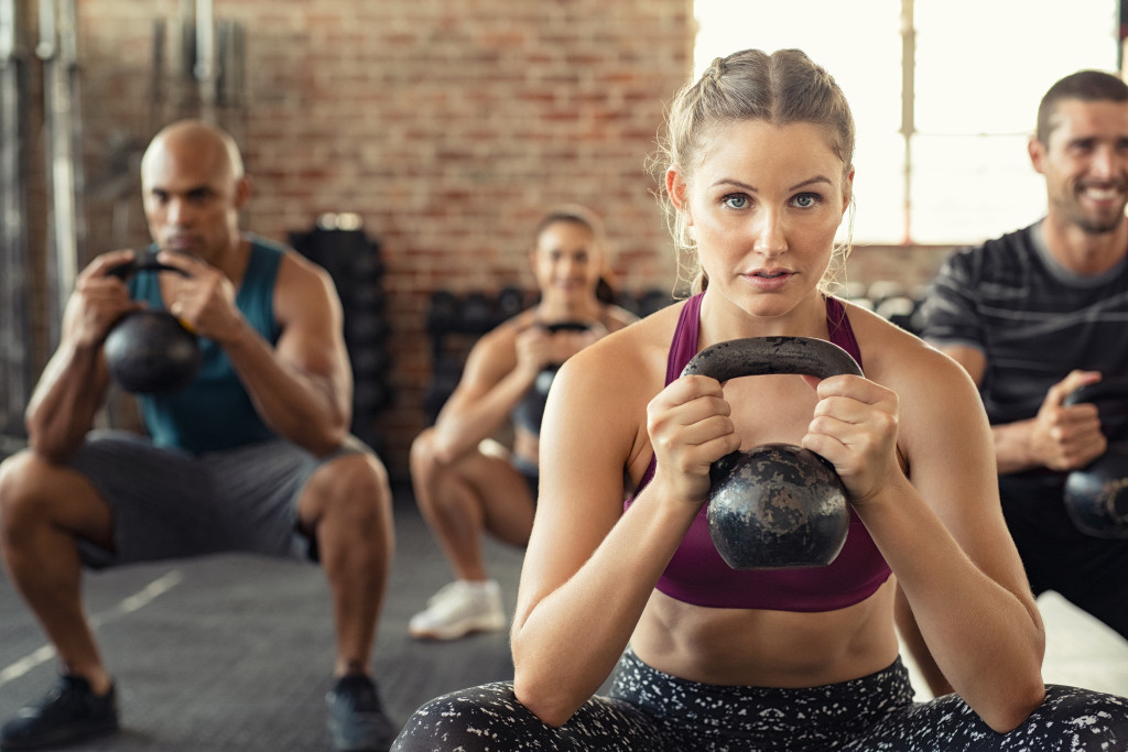 group of people lifting kettlebell during training