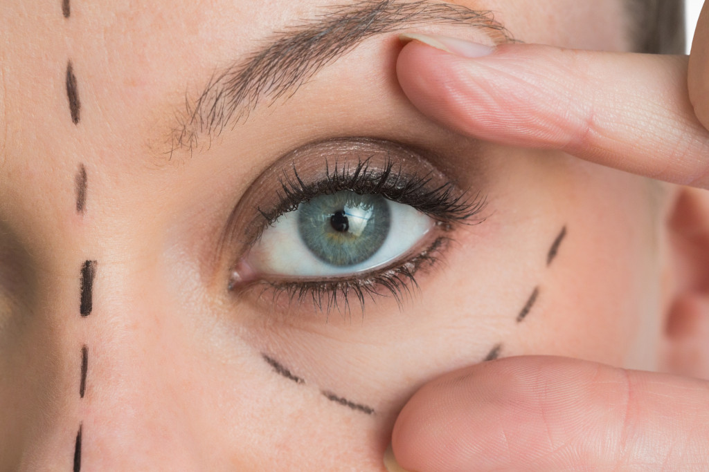 woman with green eyes opening her eyes with her fingers with lines around it